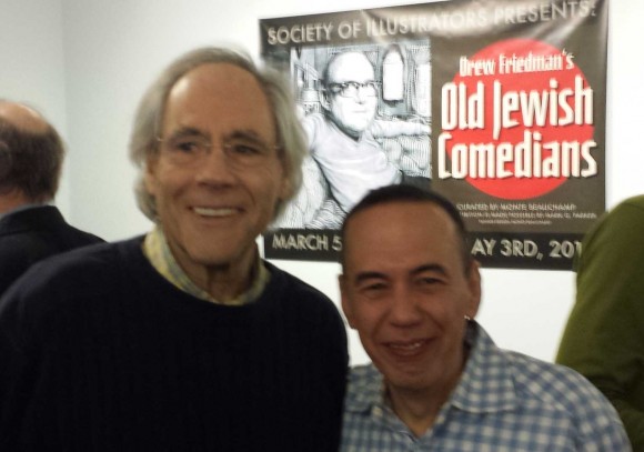 Comedians Robert Klein and Gilbert Gottfried in front of the Old Jewish Comedians Banner featuring Friedman's illustration of the late great Jack Benny.